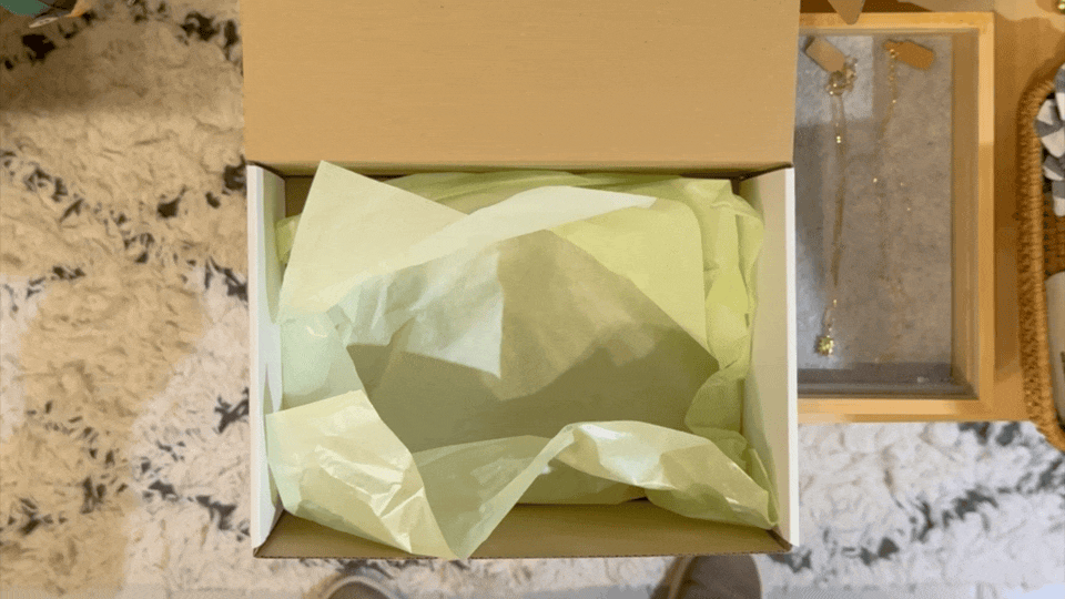 hands placing wallet, toy, soap, and chocolate into a gift box