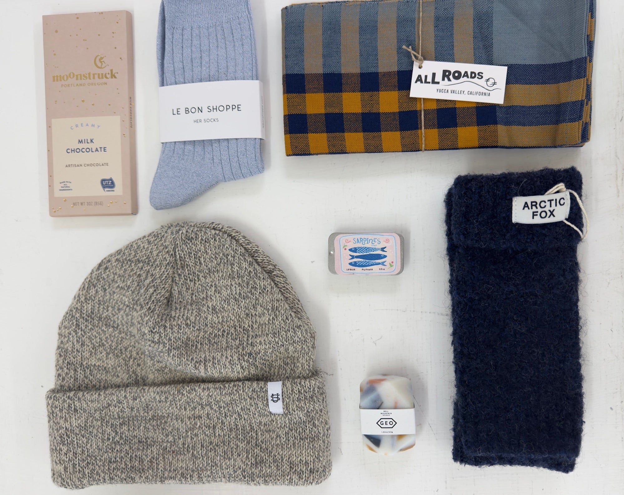 Collection of winter accessories including a beanie, socks, and a scarf on a white background.